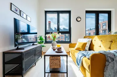 a living room with a yellow couch and windows at Prague Days - Bright Studio with Balcony, Netflix and 70Mbs WiFi in Smíchov in Prague