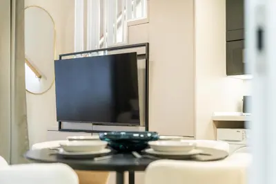 a living room with a tv and a table with chairs at Rentero Lublanska Residence - Stylish Lofts in Prague