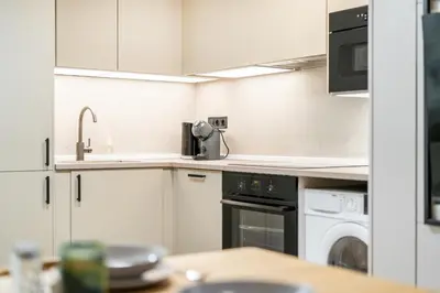 a kitchen with white cabinets and a washer and dryer at Rentero Lublanska Residence - Stylish Lofts in Prague