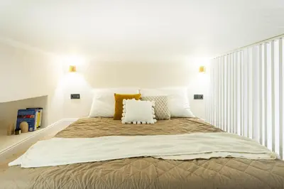 a white bedroom with a large bed with pillows at Rentero Lublanska Residence - Stylish Lofts in Prague