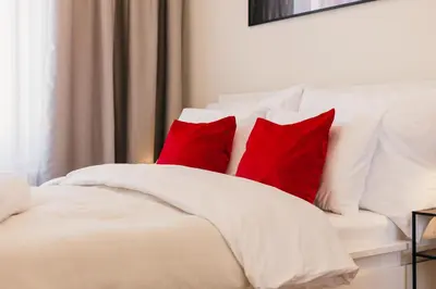 a white bed with four red pillows on it at Maisonette with terrace and view of Prague Castle in Prague