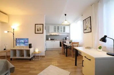 a living room with a desk and a kitchen at Bright & Cozy Apartment with Netflix & Xbox! in Kladno