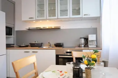 a kitchen with white cabinets and a table with chairs at Bright & Cozy Apartment with Netflix & Xbox! in Kladno