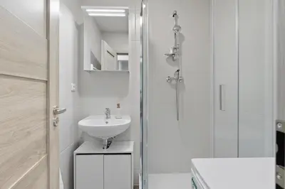 a white bathroom with a sink and a shower at Family apartment with kitchen near the subway in Prague