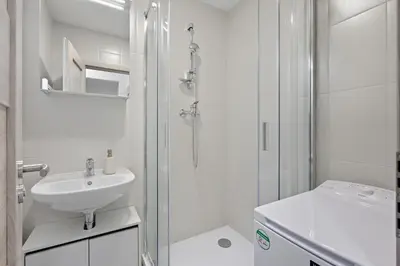a white bathroom with a shower and a sink at Family apartment with kitchen near the subway in Prague