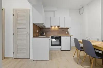 a kitchen with white appliances and a table and chairs at Family apartment with kitchen near the subway in Prague