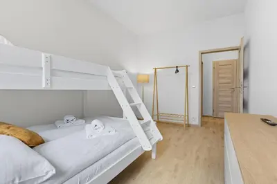 a bedroom with a white bunk bed with a ladder at Family apartment with kitchen near the subway in Prague