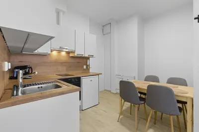 a kitchen with a sink and a table with chairs at Family apartment with kitchen near the subway in Prague