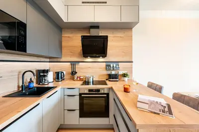 a kitchen with white cabinets and a wooden counter top at Prague Days - One-Bedroom Apartment with Balcony, Garage & 250 Mbs WiFi in Prague