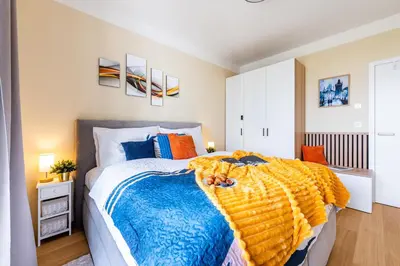 a bedroom with a bed with a blue and yellow blanket at Prague Days - One-Bedroom Apartment with Balcony, Garage & 250 Mbs WiFi in Prague