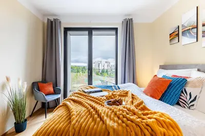 a bedroom with a bed with an orange blanket and a window at Prague Days - One-Bedroom Apartment with Balcony, Garage & 250 Mbs WiFi in Prague