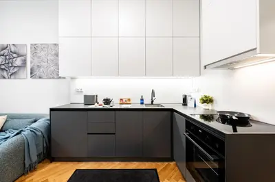 a kitchen with white cabinets and a black counter top at Prague Days - One-Bedroom Apartment with Netflix in Holešovice in Prague