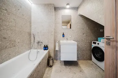 a bathroom with a tub and a sink and a washing machine at Prague Days - Top Floor Apartments with Terrace & AC near Vyšehrad Castle in Prague