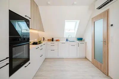 a kitchen with white cabinets and a black appliances at Prague Days - Top Floor Apartments with Terrace & AC near Vyšehrad Castle in Prague