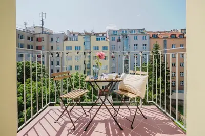 a table on a balcony with a view of buildings at Prague Days - Top Floor Apartments with Terrace & AC near Vyšehrad Castle in Prague