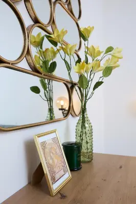 a table with a vase with flowers and a picture at Mucha Residence - with free weekend parking in Prague