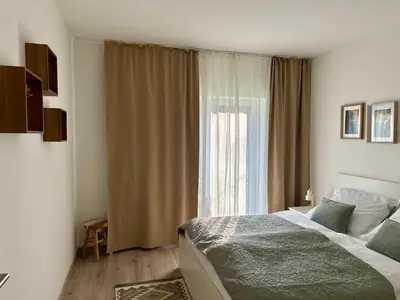 a bedroom with a bed and a large window at Prague Airport Apartment in Tuchoměřice