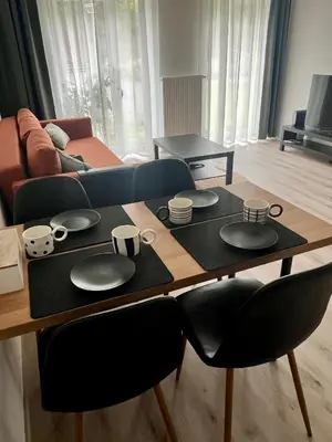 a table with plates and cups on it in a living room at Prague Airport Apartment in Tuchoměřice