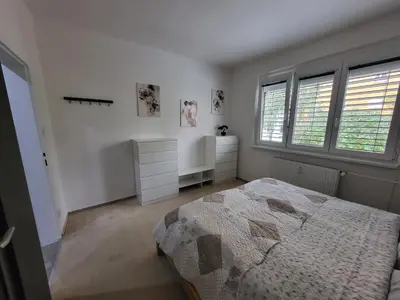 a white bedroom with a bed and two windows at Fox Den Prague in Prague