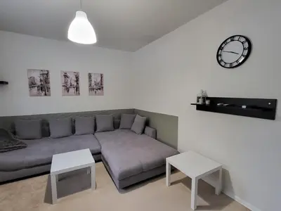 a living room with a couch and a clock on the wall at Fox Den Prague in Prague