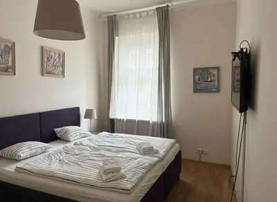 a bedroom with a bed with a television and a window at Petrska Cozy 2 bedroom apartment near Old Town in Prague