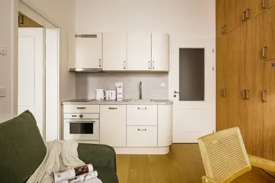 a kitchen with white cabinets and a couch in a room at Modern design studio with fast WI-FI in Prague