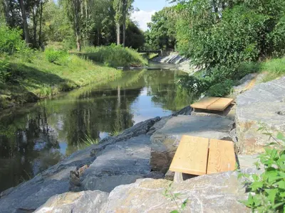two benches sitting on the side of a river at Prague house in Green Oasis 10min to the downtown in Prague