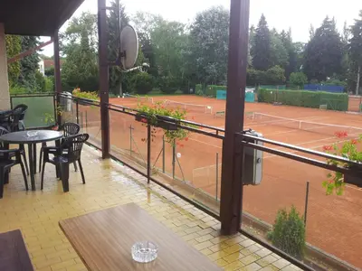 a balcony with a tennis court with a table and chairs at Penzion Tenis in Poděbrady