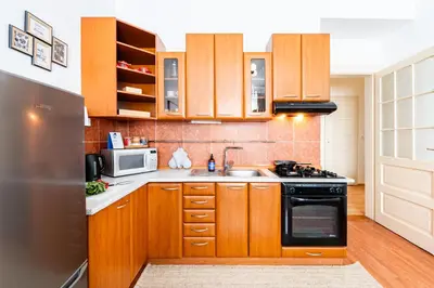 a kitchen with wooden cabinets and a sink and a microwave at Prague Days - One-Bedroom Apartment with TV, Netflix and High-Speed Wi-Fi in Vinohrady in Prague