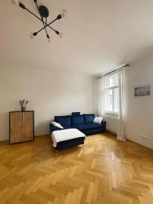 a living room with a blue couch and a wooden floor at Apartmá in Prague