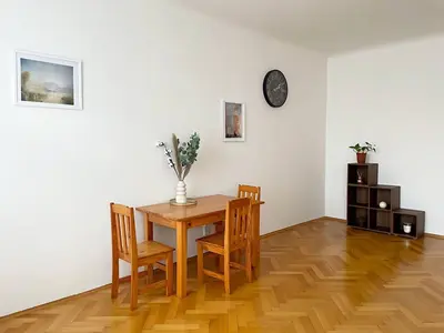 a dining room table with chairs and a clock on a wall at Apartmá in Prague