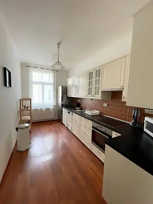 a kitchen with white cabinets and a wooden floor at Apartmá in Prague