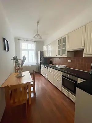a kitchen with white cabinets and a table and a dining room at Apartmá in Prague