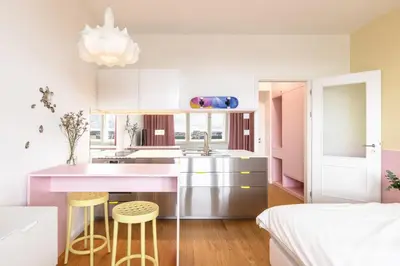 a kitchen with pink and white cabinets and stools at Prague Center Studio in Prague