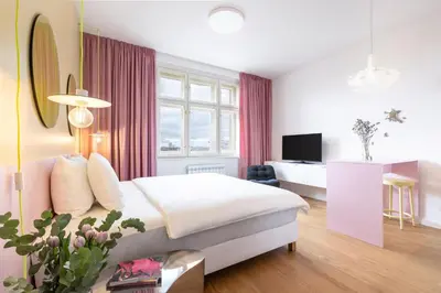 a bedroom with pink curtains and a table with a vase of flowers at Prague Center Studio in Prague