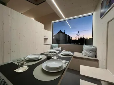 a dining room with a table and a large window at Stylish tiny house in an urban oasis in Prague