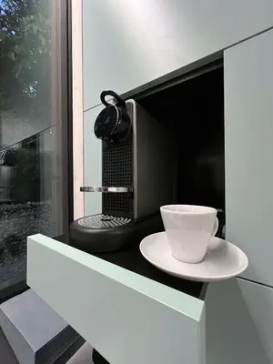 a cup on a plate in front of a microwave at Stylish tiny house in an urban oasis in Prague