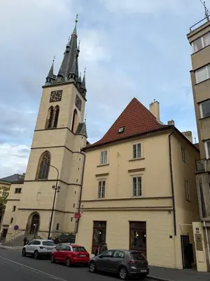 a building with a clock tower and cars parked on the street at Romantic Apartment in historical house from 1398 in Prague city centre in Prague