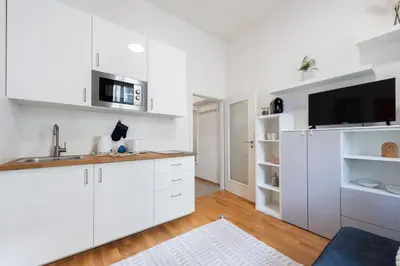 a kitchen with white cabinets and a flat screen tv at Bella Vita in Prague