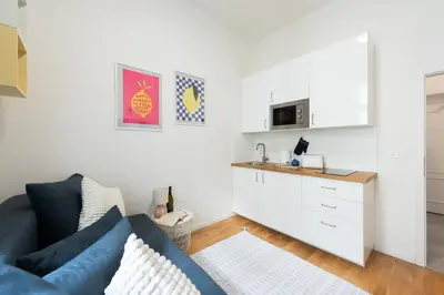 a living room with a blue couch and a kitchen at Bella Vita in Prague