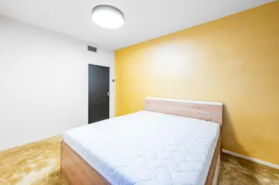 a bed in a room with a yellow wall at Urban Oasis Stodůlky in Prague