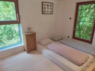 a room with a bed and a table and two windows at Romantický domek Slapy