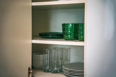 a pantry with green plates and glasses on a shelf at The Green Loft Studio - 10 min to City Center in Prague