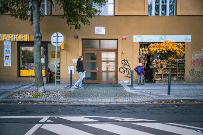 a woman walking down a street in front of a building at The Green Loft Studio - 10 min to City Center in Prague