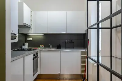 a kitchen with white cabinets and stainless steel appliances at The Green Loft Studio - 10 min to City Center in Prague
