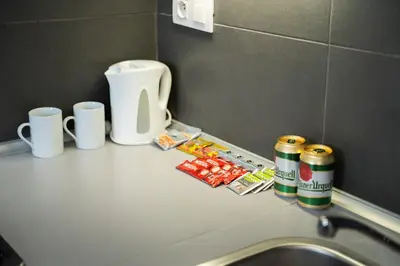 a bathroom counter with a sink and two cups and candy at The Green Loft Studio - 10 min to City Center in Prague