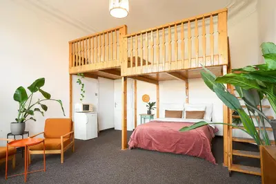 a bedroom with a loft bed with a red bedspread at Muze Suites in Prague
