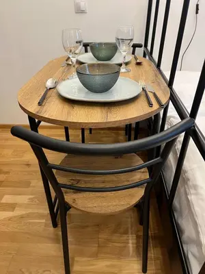 a wooden table with a plate and wine glasses on it at Urban Nest On Tyrsova 7 - Near IP Pavlova Metro in Prague