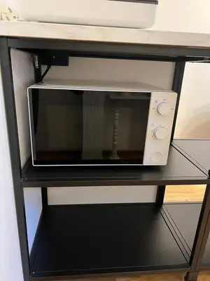 a microwave oven sitting on a black shelf at Urban Nest On Tyrsova 7 - Near IP Pavlova Metro in Prague