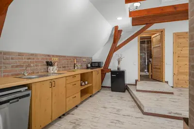 a kitchen with wooden cabinets and a brick wall at Statek Luigi in Tuchlovice